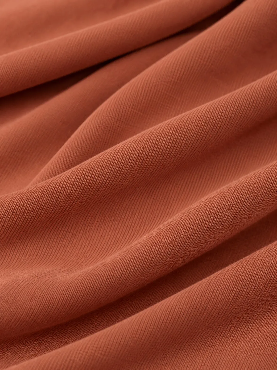 Bamboo jersey hijab fabric texture close-up — terracotta colour knit surface detail