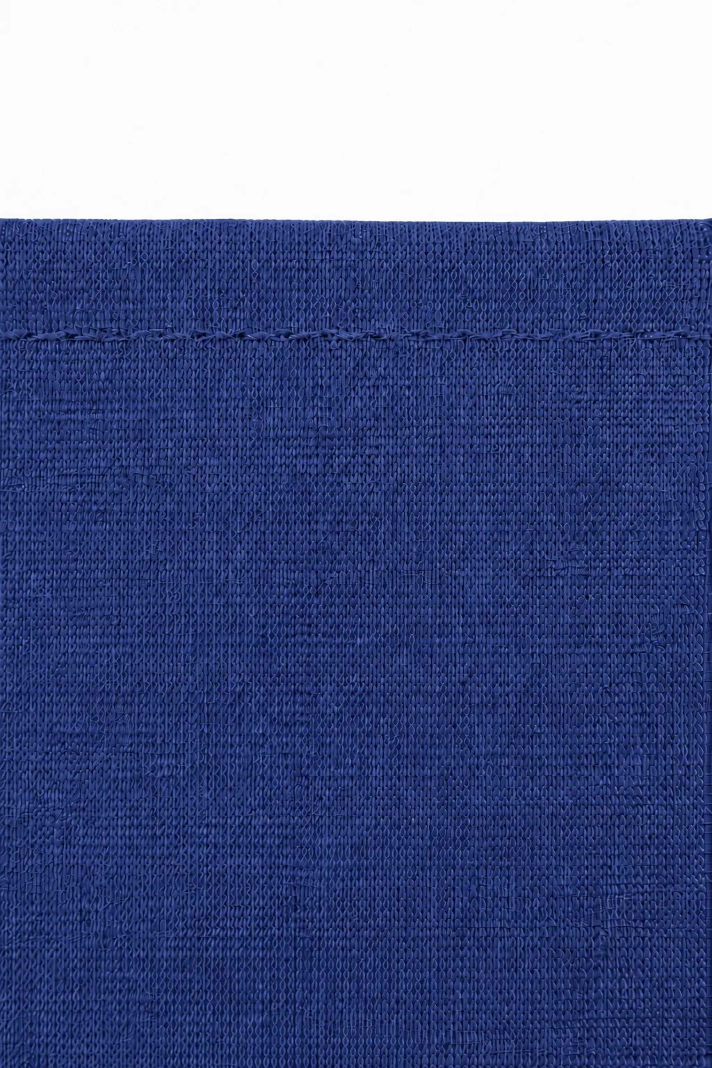 Cotton jersey hijab fabric close-up — royal blue open-weave knit texture and overlock hem stitch detail