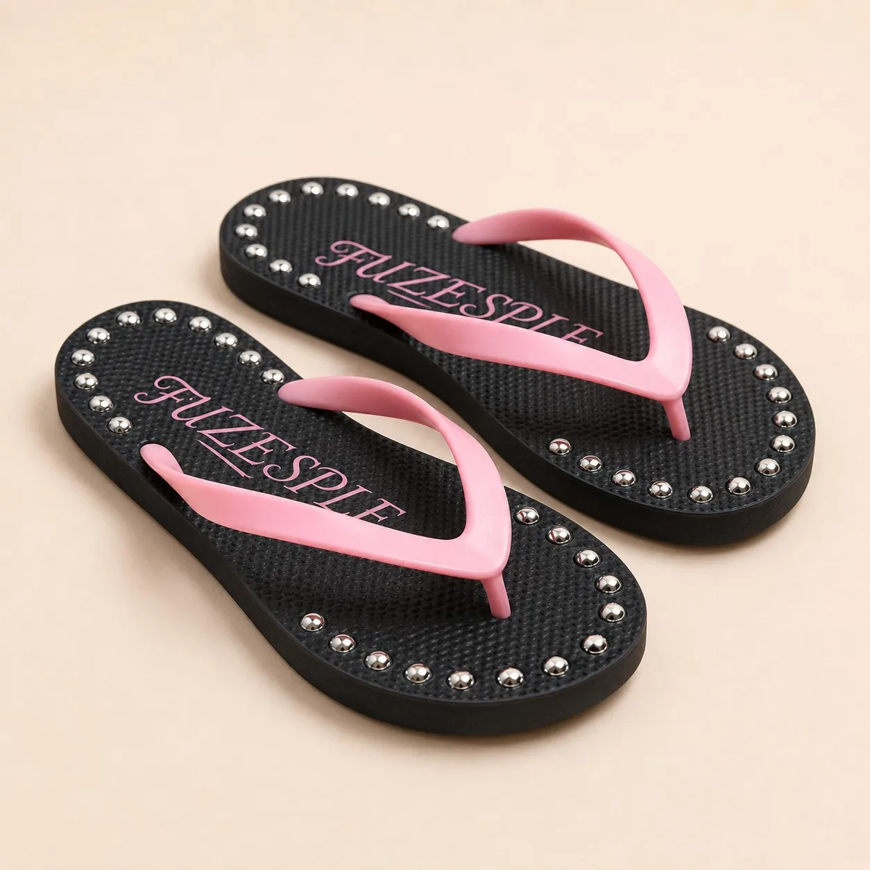 Angled view of black and pink studded flip flops with PVC straps