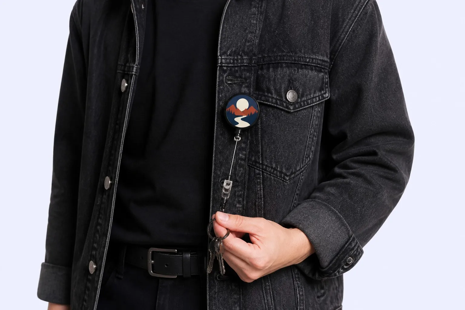 On-body wear — badge reel keychain pinned to denim jacket, cord extended with keys