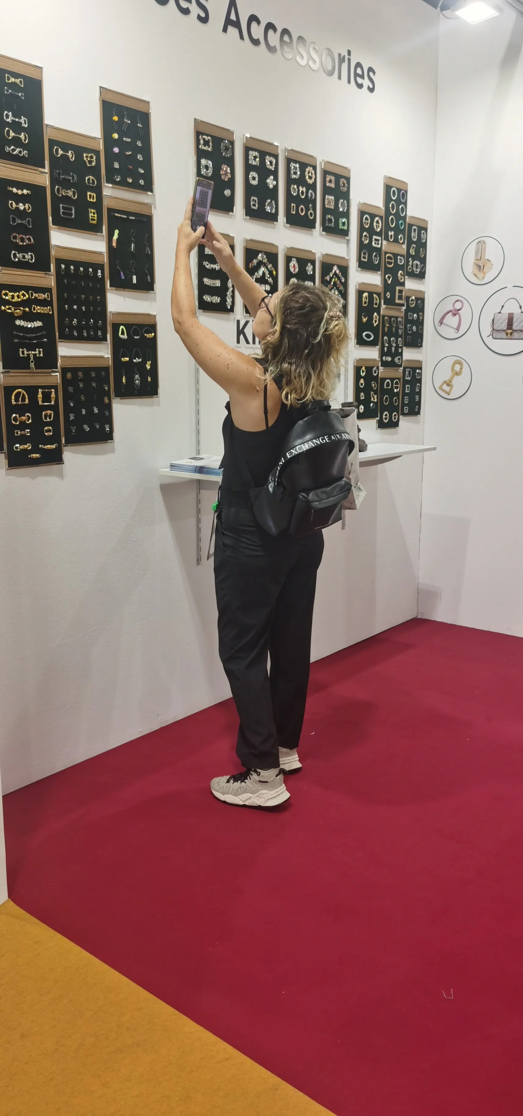 International visitor photographing bag and shoe hardware samples displayed at KingMing Hardware's booth during a past LINEAPELLE Milan exhibition