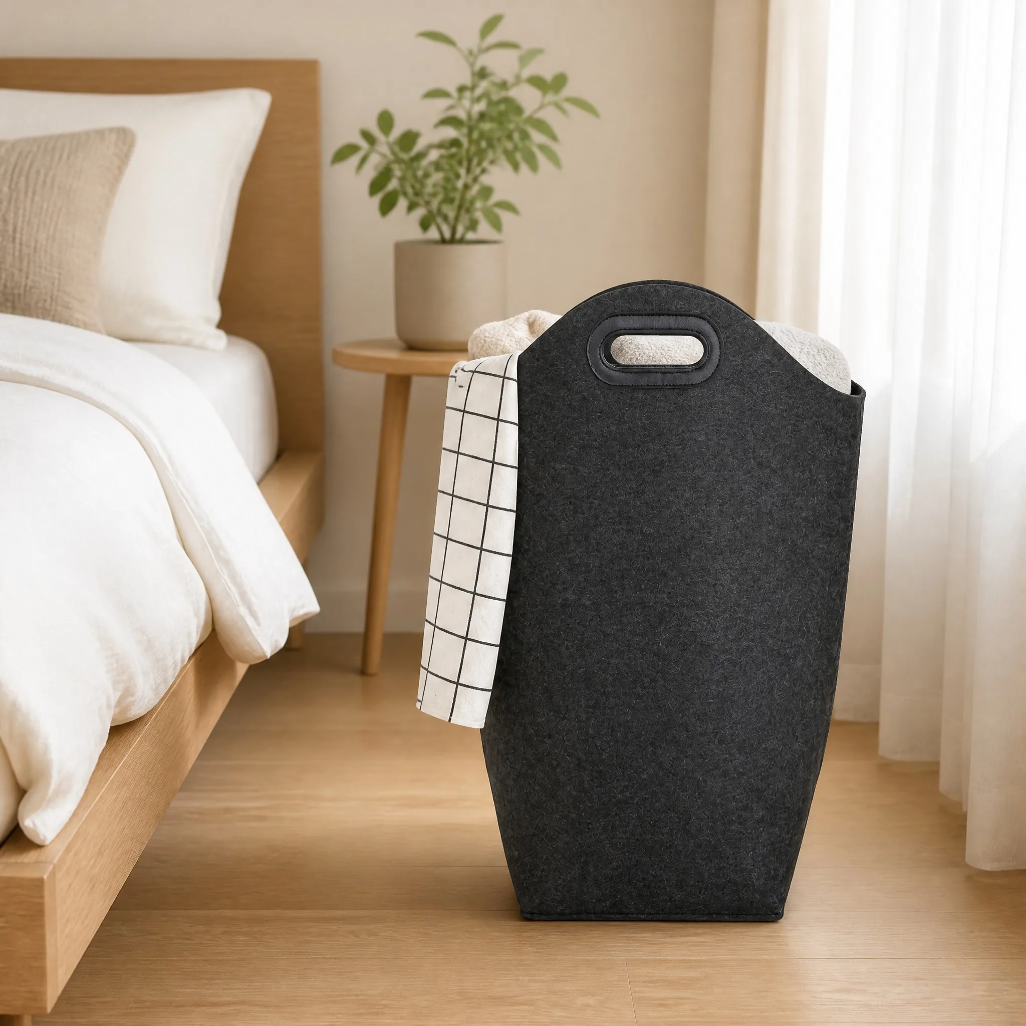 Felt laundry basket beside a bed for bedroom clothing storage