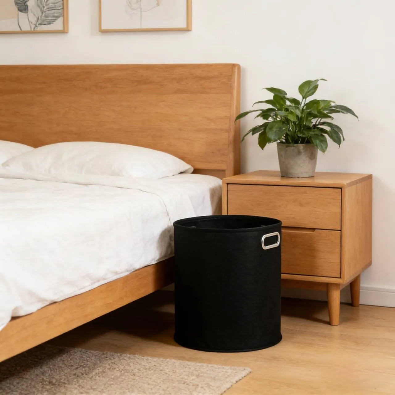 Black felt laundry hamper styled beside a wooden bed