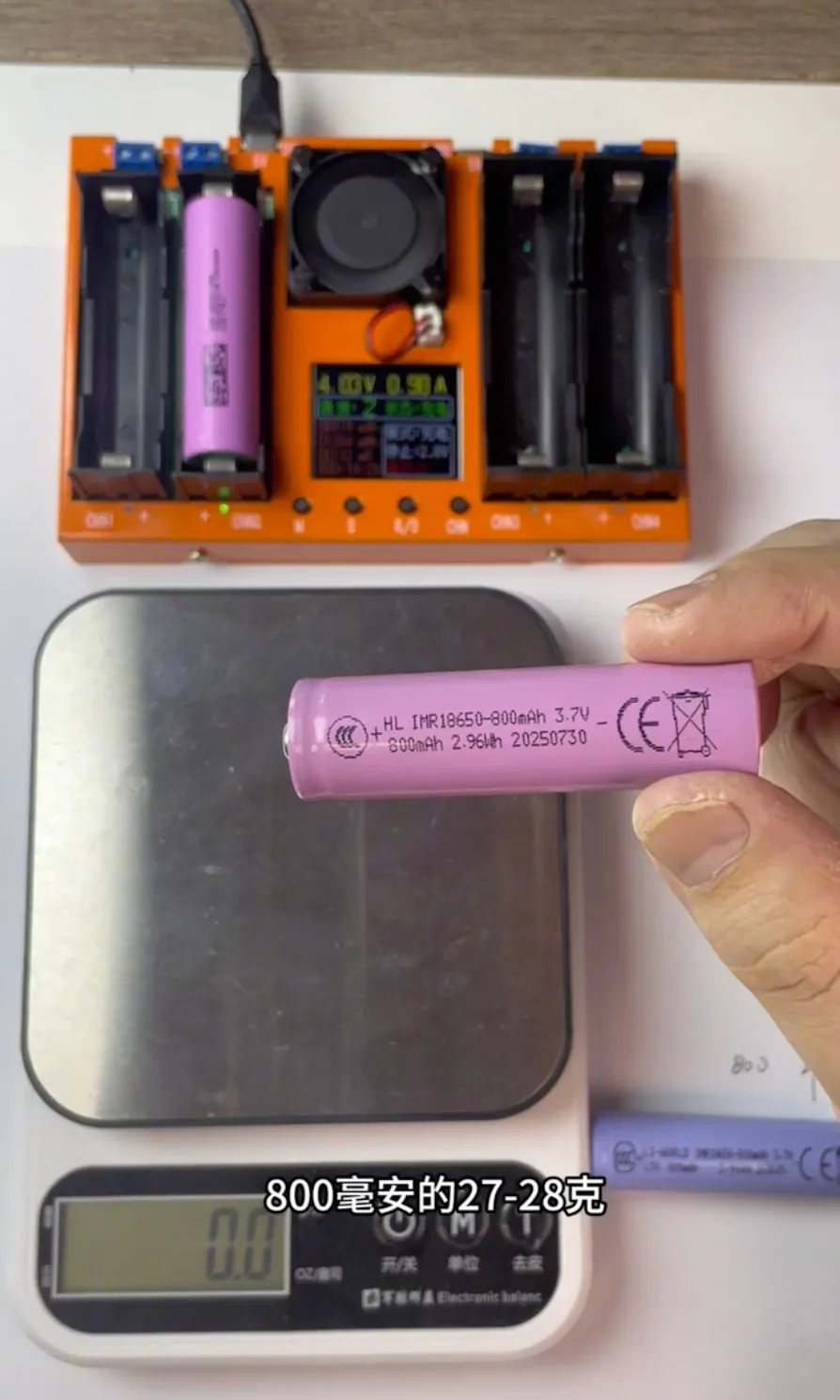 800mAh 18650 battery sample measuring 27.7g on a digital scale.