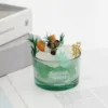 Taza individual verde estilo cristal con flor seca.