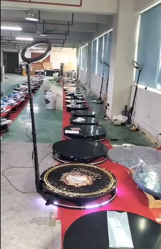 Factory worker assembling a 360 photo booth on a production line with rotating arm components visible