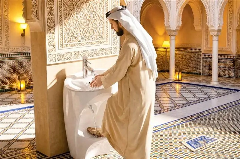 Man performing wudu at a wash station in an ornate mosque washroom