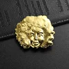 Broche dorado con diseño de rostro femenino en 3D.