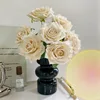 7 rosas blancas en un jarrón de cristal negro.