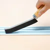 A black crevice brush with a wooden handle.