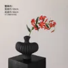 Textured vase with black flame lilies and a single red lily