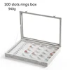 Caja gris para anillos con 100 ranuras.