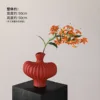Textured vase with red flame lilies and an orange stem