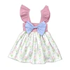 Vestido de niña con estampado de tulipanes, lazo azul y hombros descubiertos en rosa.