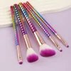 5 unidades de cepillos con mango degradado de colores, base blanca y cerdas moradas.