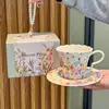 Tazza da crema pasticcera con valle di fiori da sogno, piattino, cucchiaio, scatola portatile