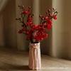 A ladylike pink vase with five red plum blossoms