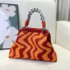 Bolso dumpling con diseño ondulado en tonos naranja rojizo.