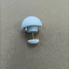 Botón blanco en forma de hongo con una sola aguja de coser de tela.
