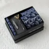 Conjunto de caja de regalo KK con plumas blancas y fondo azul.