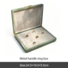 Caja para anillos con asa de metal verde.
