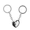 Un par de llaveros de gato en blanco y negro con forma de corazón.