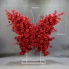 Arreglo floral de mariposas y rosas rojas con soporte con ruedas.