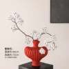 Textured vase with red pear blossoms and a white stem