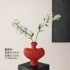 Textured vase with red flame lilies and 2 white stems