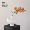Textured vase with white flame lilies and an orange stem