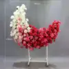 Rosas rojo-rosadas, lirios, luna, diseño floral con soporte.