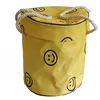 Bolso tipo cubo de juguete con carita sonriente amarilla.