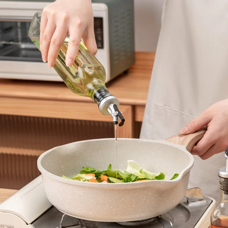 Lever-operated glass oil bottle shown while pouring