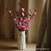 A lady's white vase with 5 pink plum blossoms