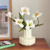Cinco tulipanes blancos floreciendo en un jarrón con pétalos color crema
