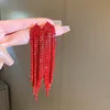 Pendientes de borla con aguja plateada y flecha roja.