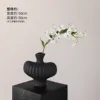 Textured vase with black flame lilies and a single white lily