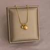 Collana in acciaio al titanio con doppia sfera dorata