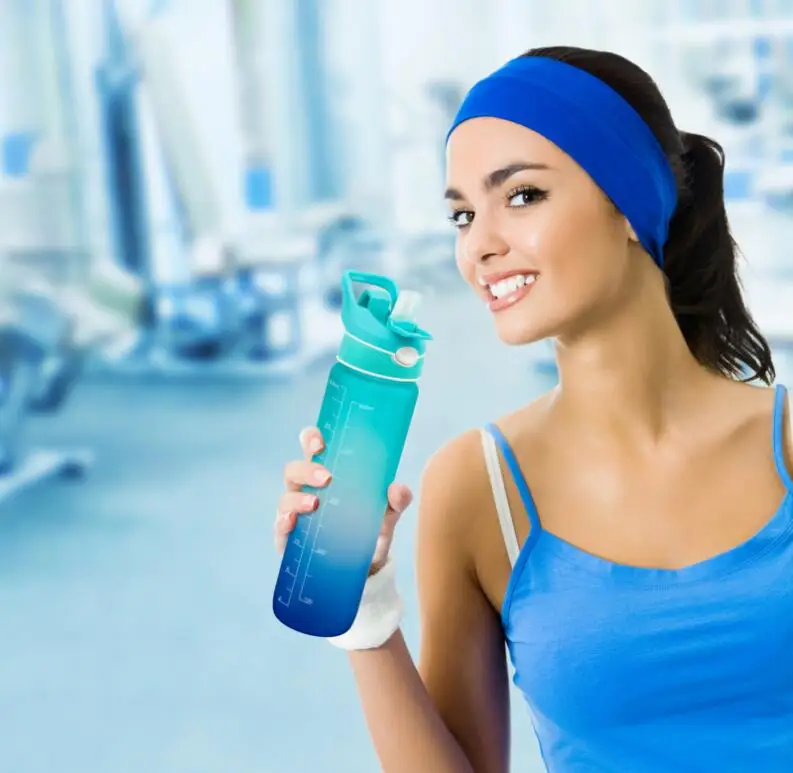 Attractive Sporty Young Woman Drinking from Blue Shaker Bottle in