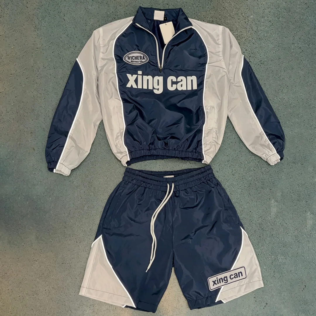 Fabriksproduceret tilpasset herretøj i vintage-stil: farveblok-udformet halvzip-vindjakke og korte bukser i kort model, fritidssportstøjsæt med DTG-digital print