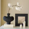 Textured vase with black pear blossoms and a white stem