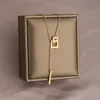 Collana in acciaio al titanio con doppio anello quadrato dorato e nappina