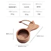 Cuchara medidora de café de madera maciza con forma de cola de pez.