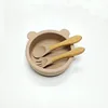 Ciotola in silicone a forma di orsetto, color marrone chiaro, con manico in legno e cucchiaio.