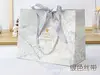 White cardboard; 067 silver ribbon; Medium 25.20.12.5.