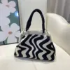 Bolso dumpling con diseño ondulado en blanco y negro.