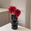 Black vase with two daisies and red flowers