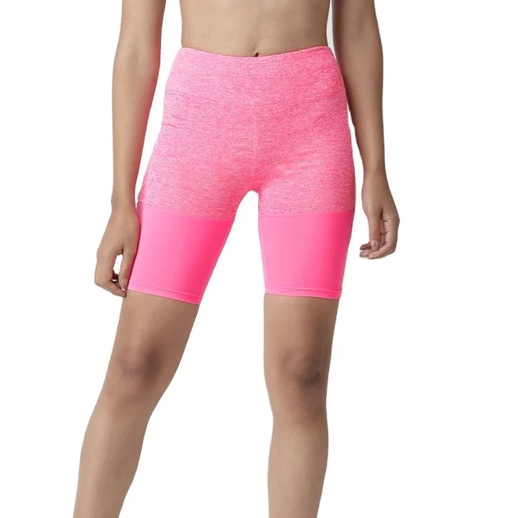 Una mujer deportiva seria que viste pantalones cortos negros ajustados y  una camiseta sin mangas está de puntillas después de un entrenamiento. una  chica rubia fitness está posando en un gimnasio. 